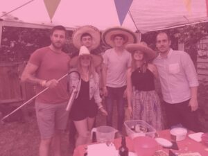 Group shot at Blues and Rock apprentice challenge team selling nachos and wearing mexican style hats for charity with pink image overlay