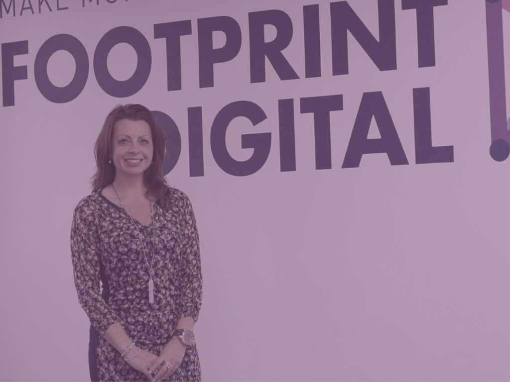 Liz Flavell standing in front of the footprint digital sign in the office with purple image overlay