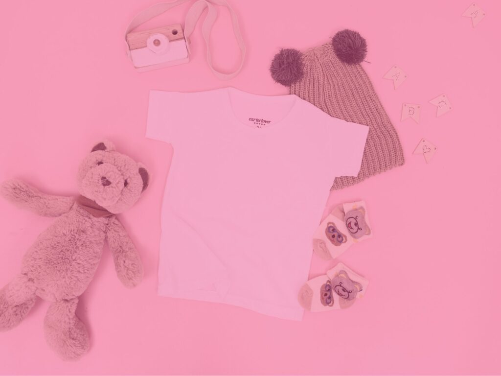 Pink baby clothes and teddy laid out