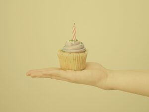 Yellow birthday cupcake with frosting and candle